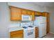 Well-lit kitchen with white appliances, wood cabinets, and quartz countertop at 8501 W University Ave # 2020, Las Vegas, NV 89147