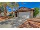 Wide driveway leads to an attached two-car garage, framed by mature trees and a tidy front yard at 872 Linn Ln, Las Vegas, NV 89110