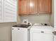 Bright laundry area with a white washer and dryer beneath wooden cabinets at 10556 Nantucket Ridge Ave, Las Vegas, NV 89166