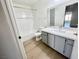 Bright bathroom features white tub/shower combo, toilet and sink with grey vanity at 1150 N Buffalo Dr # 1005, Las Vegas, NV 89128