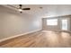 Spacious living room with light-colored walls, a ceiling fan, wood flooring, and natural light from a window and glass door at 2110 Bavington Dr # C, Las Vegas, NV 89108