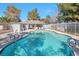 Community pool with crystal clear water, surrounded by lounge chairs and mature trees under a sunny sky at 2110 Bavington Dr # C, Las Vegas, NV 89108