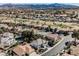 A high-angle shot captures a neighborhood with houses next to a golf course, under a sunny, mountainous landscape at 2493 Ram Crossing Way, Henderson, NV 89074