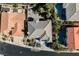 A high angle captures a tan roofed house between two houses, one with a pool, on a sunny day at 2493 Ram Crossing Way, Henderson, NV 89074