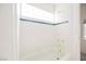 Bright bathroom features a tub with white tile, blue accent stripe, and gold fixtures at 2493 Ram Crossing Way, Henderson, NV 89074