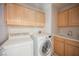 Well-lit laundry room with front loading washer, dryer, sink, and light wood cabinets at 2493 Ram Crossing Way, Henderson, NV 89074