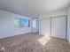 Bright bedroom featuring neutral carpet, a large window, and sliding closet doors at 3251 Southridge Ave, Las Vegas, NV 89121
