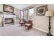 Cozy living room featuring a fireplace with lit logs, carpet, and large window views at 3901 W Red Coach Ave, North Las Vegas, NV 89031
