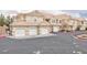 Exterior view of tan townhomes featuring multiple garages with white doors and terra cotta roofing at 5855 Valley Dr # 2018, North Las Vegas, NV 89031
