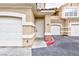 Tan townhome entry featuring a white door, red trim, and a two car garage at 5855 Valley Dr # 2018, North Las Vegas, NV 89031