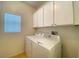 Bright laundry room featuring white washer, dryer, and cabinetry for ample storage at 6240 Winston Falls Ave, Las Vegas, NV 89139