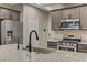 Close up view of a kitchen island with granite countertop, stainless steel sink, and modern fixtures at 6679 Salt Pond Bay St, Las Vegas, NV 89149