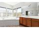 Bright bathroom featuring a soaking tub, oak cabinets, and a large mirror with great natural light at 7808 Foothill Ash Ave, Las Vegas, NV 89117