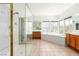 Well-lit bathroom with a glass shower, soaking tub, oak cabinets, tile flooring, and large mirrors at 7808 Foothill Ash Ave, Las Vegas, NV 89117