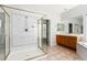 Well-lit bathroom with a glass shower, oak cabinets, tile flooring, and large mirrors at 7808 Foothill Ash Ave, Las Vegas, NV 89117