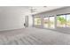 Bright and airy living room with neutral tones, plush carpeting, ceiling fan, and sliding glass doors to the backyard at 7808 Foothill Ash Ave, Las Vegas, NV 89117