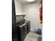 Modern laundry room features gray wood-look flooring, black cabinets, and black stainless steel machines at 8113 Mineola Palms St, Las Vegas, NV 89139