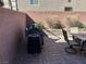 Outdoor living and dining with a built in gas grill, a table with chairs and red brick hardscape at 8113 Mineola Palms St, Las Vegas, NV 89139