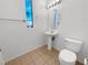 Bright bathroom featuring tile floors, a pedestal sink, a toilet, a contemporary mirror and light fixtures at 8962 Rufina St, Las Vegas, NV 89148