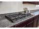 Gas cooktop with a stainless steel hood, rich wood cabinetry and granite counters at 9643 Ponderosa Skye Ct, Las Vegas, NV 89166