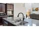 Kitchen island with a stainless steel sink, black faucet and seating area, and open view to the living area at 9643 Ponderosa Skye Ct, Las Vegas, NV 89166