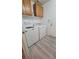 Bright laundry room with front loading washer and dryer, storage cabinets and wood-look flooring at 1147 Light Sky Ave, Henderson, NV 89074