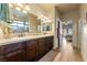 Bathroom with granite counters, double sinks, dark cabinets, and a view of the bedroom at 150 Spruce Ln, Pahrump, NV 89048