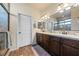 Bathroom featuring dual sinks with granite counters, dark wood cabinets, and tiled shower at 150 Spruce Ln, Pahrump, NV 89048