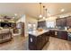 Bright kitchen features dark wood cabinets, an island with granite countertop, stainless steel appliances and wood tile flooring at 150 Spruce Ln, Pahrump, NV 89048