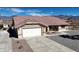 Front exterior view of single story home with two-car garage and desert landscaping with small water fountain at 2080 Mount Charleston Dr, Pahrump, NV 89048