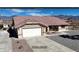 Front exterior view of single story home with two-car garage and desert landscaping with small water fountain at 2080 Mount Charleston Dr, Pahrump, NV 89048