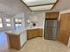 Kitchen with tile countertops, wooden cabinets, fireplace in adjacent living room, and stainless steel refrigerator at 2080 Mount Charleston Dr, Pahrump, NV 89048