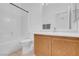 Bright bathroom featuring a bathtub, toilet, vanity, and sink with wood cabinets and a large mirror at 240 Ember St, Pahrump, NV 89048