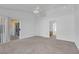 Bright primary bedroom featuring neutral carpet, a ceiling fan, and a doorway to the bathroom at 240 Ember St, Pahrump, NV 89048