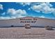 The sign reads 'Welcome to Pahrump', set against a bright blue sky with scattered clouds at 240 Ember St, Pahrump, NV 89048