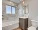 Bathroom featuring a tub with marble tile surround and glass enclosure and modern vanity at 2711 Ashby Ave, Las Vegas, NV 89102