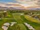 Scenic aerial view of a lush green golf course with sand traps and mountains in the background at sunset at 3026 Coveri Ct, Las Vegas, NV 89141