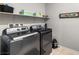 Functional laundry room with modern washer and dryer, overhead shelving, and clean tile flooring at 3862 E Summit Ave, Pahrump, NV 89061