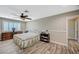 Bright bedroom featuring wood-look floors, ceiling fan, and dresser with shuttered windows at 4625 W Robindale Rd, Las Vegas, NV 89139