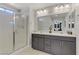 Bright bathroom with a glass-enclosed shower and double vanity with gray cabinets at 4733 Cactus Sun Ln, North Las Vegas, NV 89031