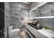 Modern bathroom with gray marble wall tiles, lighted mirror, and waterfall faucet at 667 Solitude Rock Ct, Henderson, NV 89012