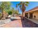 Large backyard with covered patio, mature trees, brick pavers, and landscaping at 7624 Desert Delta Dr, Las Vegas, NV 89128