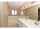 Bright bathroom featuring dual sinks, a soaking tub, and a large mirror at 7624 Desert Delta Dr, Las Vegas, NV 89128