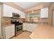 Well-lit kitchen with stainless steel appliances, tan countertops, white cabinets, and window view at 7624 Desert Delta Dr, Las Vegas, NV 89128