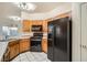 Galley kitchen with wooden cabinetry, black appliances, and tile flooring for easy cleaning at 7728 White Flower Ct, Las Vegas, NV 89131