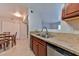 A view of the kitchen with stainless steel sink, granite countertops, wooden cabinets, and a dining area at 7885 W Flamingo Rd # 1016, Las Vegas, NV 89147