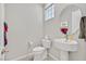 Half bath with white tile floor, pedestal sink, toilet and window with glass block detail at 8460 Carmel Ridge Ct, Las Vegas, NV 89113