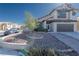 Desert landscape with two story home, wide driveway, and tree in yard under a bright sky at 8869 Dove Cove Dr, Las Vegas, NV 89129