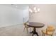 Neutral living room features a modern chandelier, wood table and chairs, and gray carpet at 1338 Ossa St, Henderson, NV 89052