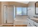 Modern bathroom with a glass-enclosed shower, separate tub, and vanity with granite countertop and white cabinets at 1800 Summit Pointe Dr, Las Vegas, NV 89117